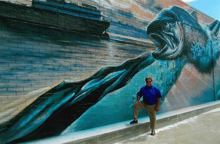 man standing in front of fish mural on wall