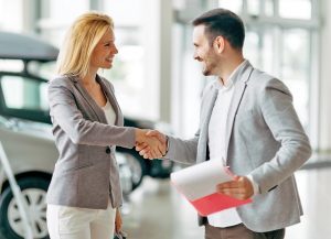 man and woman shaking hands in a dealership