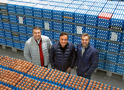 three men standing in a warehouse of eggs
