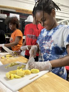 Students in the kitchen cutting fruits